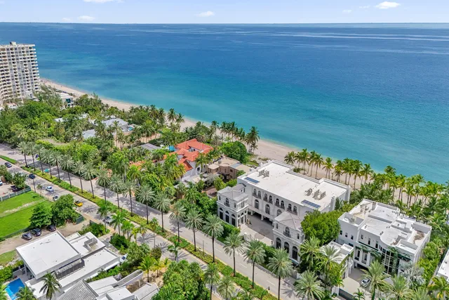 front view of house with a yard and palm trees