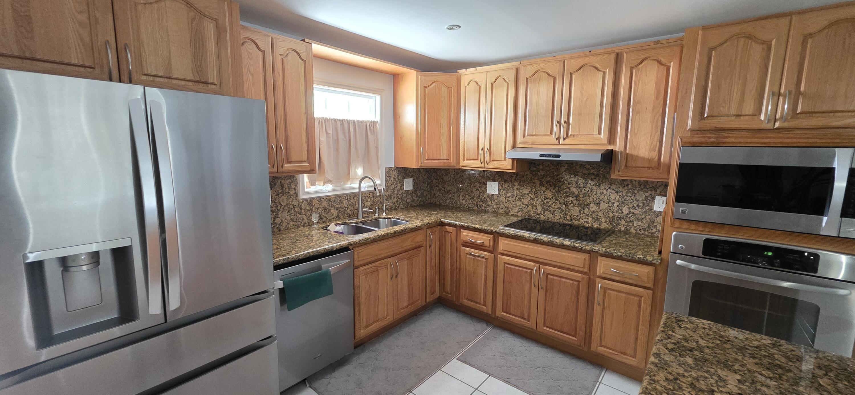 8 Emerald Drive Key West, FL 33040 - Photo 11 of 43 a kitchen with stainless steel appliances granite countertop a refrigerator a stove and a sink with wooden cabinets