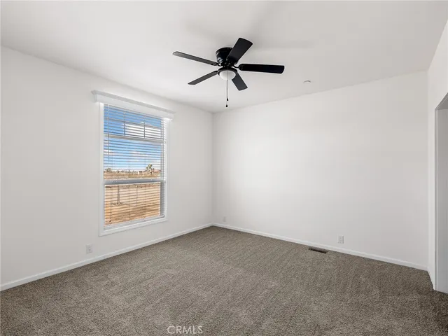 an empty room with a window and a fan