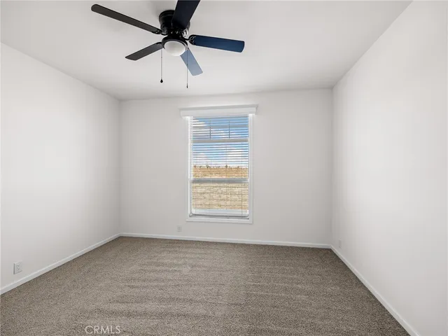 an empty room with a window and a ceiling fan