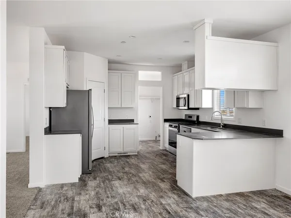 a kitchen with stainless steel appliances granite countertop a refrigerator a stove a sink and white cabinets