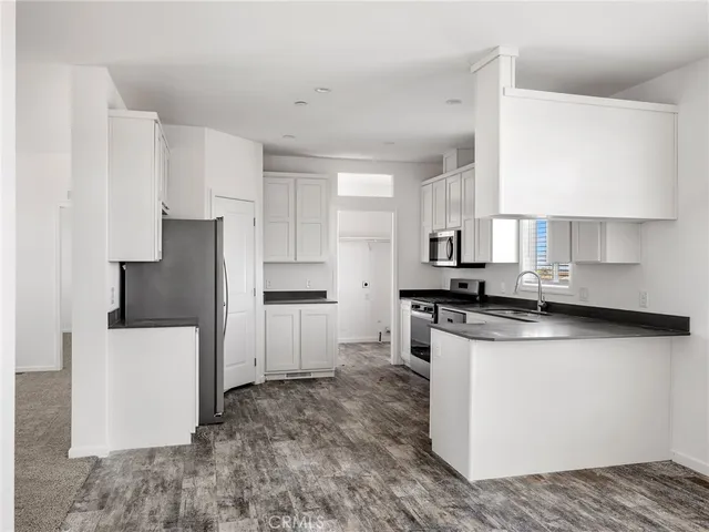 a kitchen with stainless steel appliances granite countertop a refrigerator a stove a sink and white cabinets