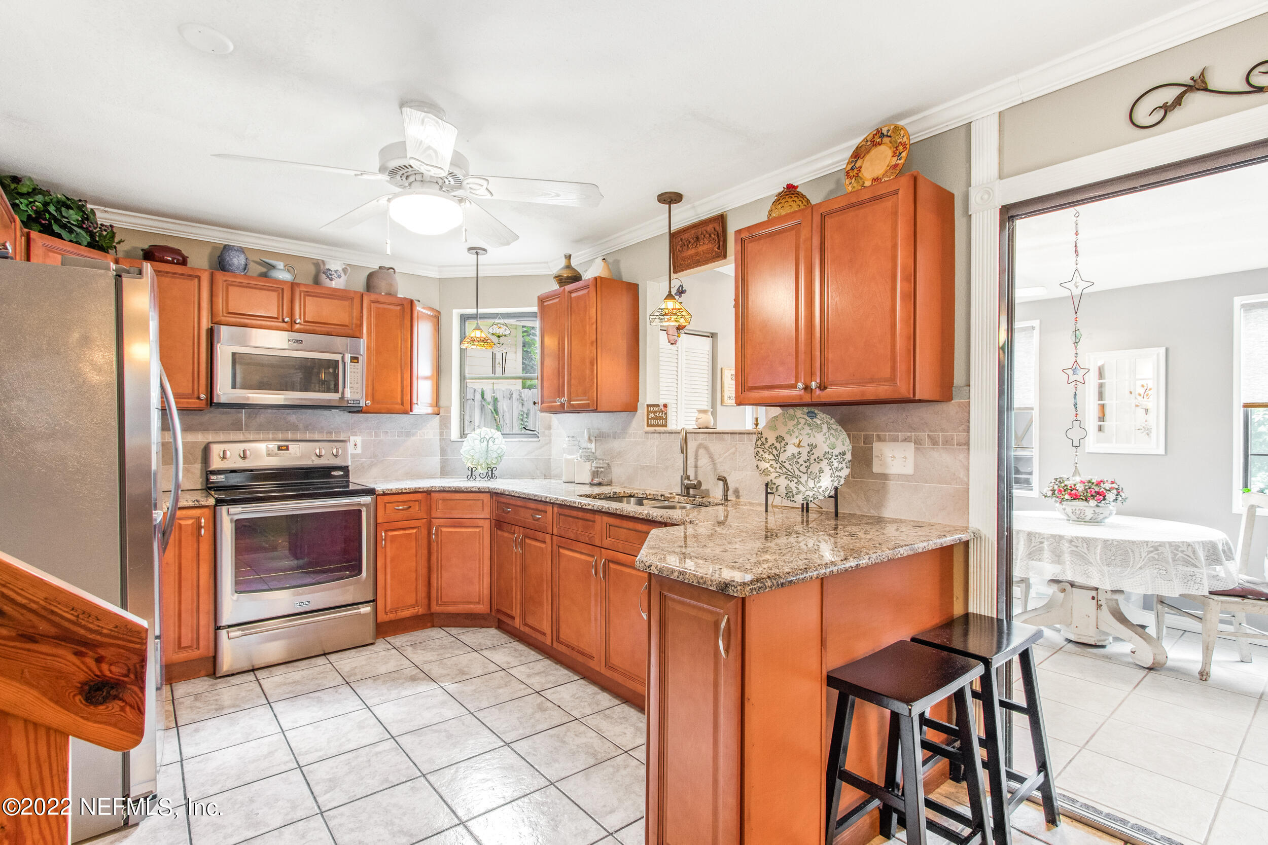 19 Madeore Street St. Augustine, FL 32084 - Photo 13 of 28 a kitchen with stainless steel appliances granite countertop a stove top oven a sink dishwasher a dining table and chairs with wooden floor
