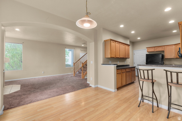 3053 Sage Loop, Unit B1 Lehi, UT 84043 - Photo 6 of 25 Open-concept living space featuring wood-finish flooring, a kitchen island with seating, recessed lighting, and warm wood cabinetry