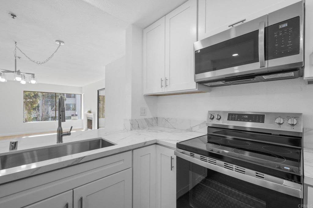 5745 Friars Road, Unit 116 San Diego, CA 92110 - Photo 11 of 44 a kitchen with stainless steel appliances granite countertop a sink a stove and microwave