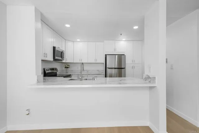 a kitchen with stainless steel appliances granite countertop a sink a stove a refrigerator a microwave and white cabinets