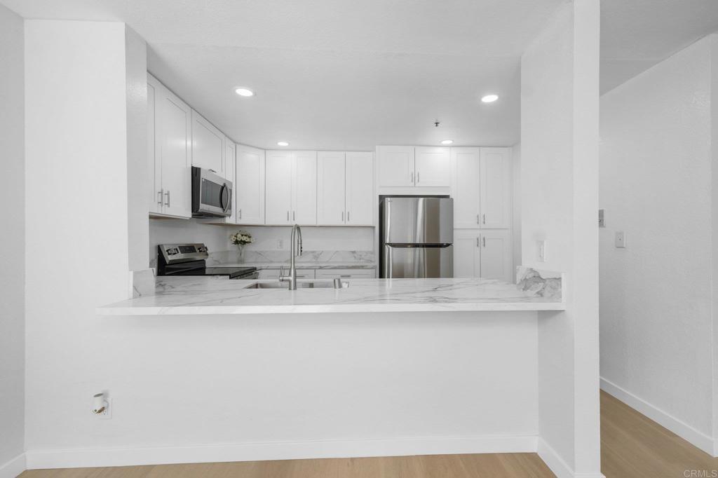 5745 Friars Road, Unit 116 San Diego, CA 92110 - Photo 9 of 44 a kitchen with stainless steel appliances granite countertop a sink a stove a refrigerator a microwave and white cabinets