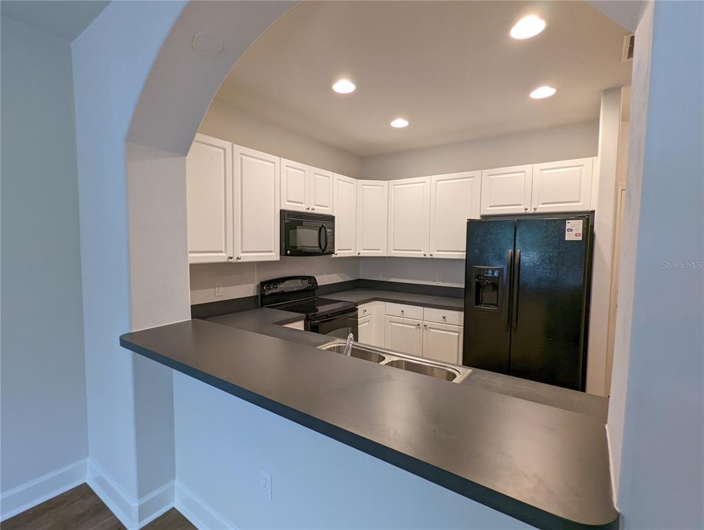 7782 Southwest 64th Lane, Unit 1002 Gainesville, FL 32608 - Photo 6 of 42 a kitchen with stainless steel appliances a refrigerator a sink a stove a microwave and cabinets