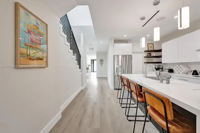 a kitchen with stainless steel appliances granite countertop a refrigerator a sink dishwasher a stove and white countertops with wooden floor