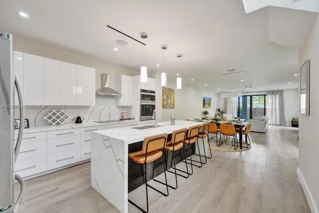 a large white kitchen with lots of furniture a sink dishwasher and white appliances with wooden floor