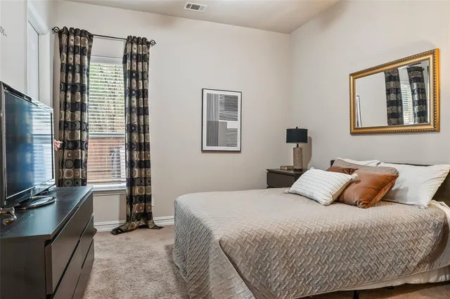 a bedroom with a bed and a flat tv screen on a dresser