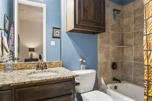 a bathroom with a granite countertop toilet a sink and a mirror