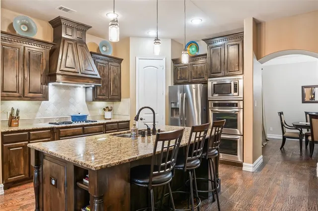 a kitchen with stainless steel appliances granite countertop a kitchen island a table and chairs