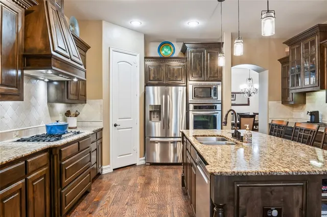 a kitchen with stainless steel appliances granite countertop a refrigerator and a stove top oven