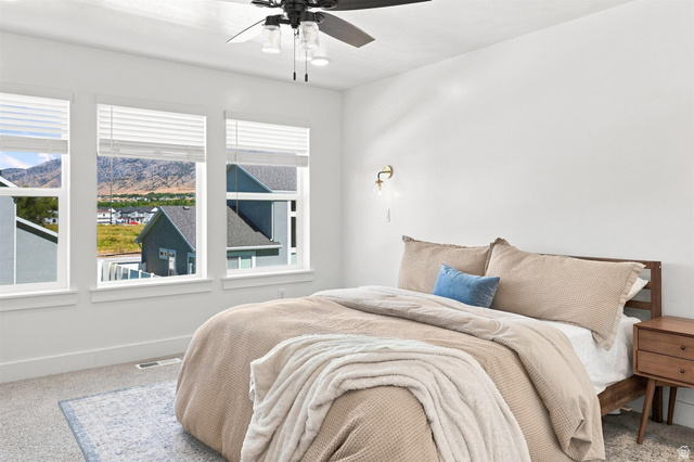 355 West 3085 South Logan, UT 84321 - Photo 23 of 40 Triple windows with blinds, wall-mounted sconce, ceiling fan with integrated lighting, and carpeted flooring