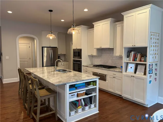 a large kitchen with stainless steel appliances granite countertop a stove a sink and a wooden floors