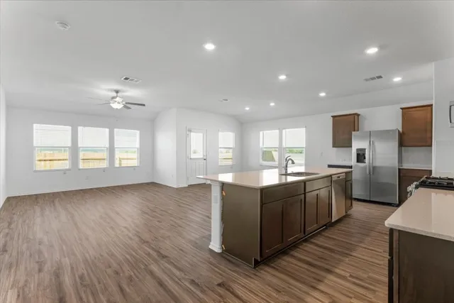 a large kitchen with stainless steel appliances granite countertop a lot of counter space and wooden floors