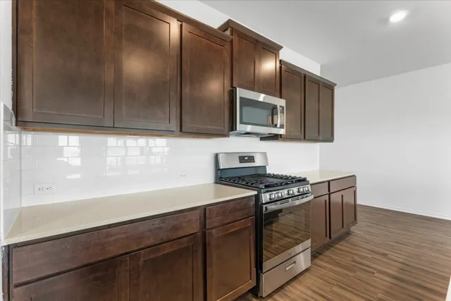 a kitchen with granite countertop cabinets stainless steel appliances and wooden floor