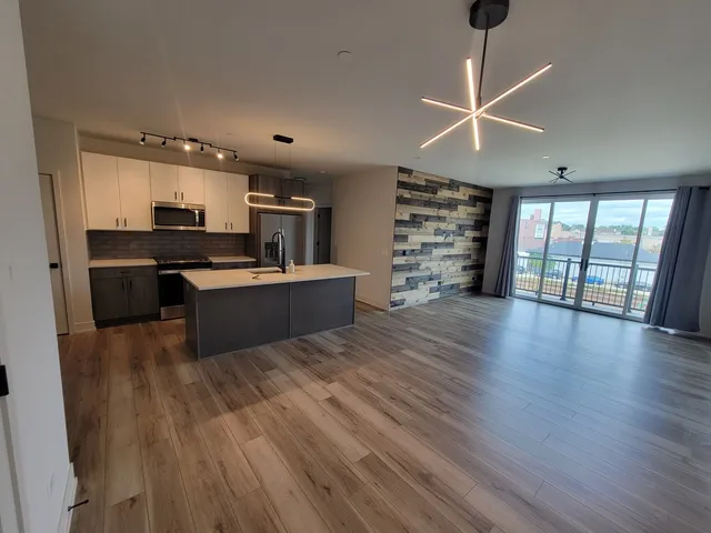 a living room with furniture a large window and wooden floor