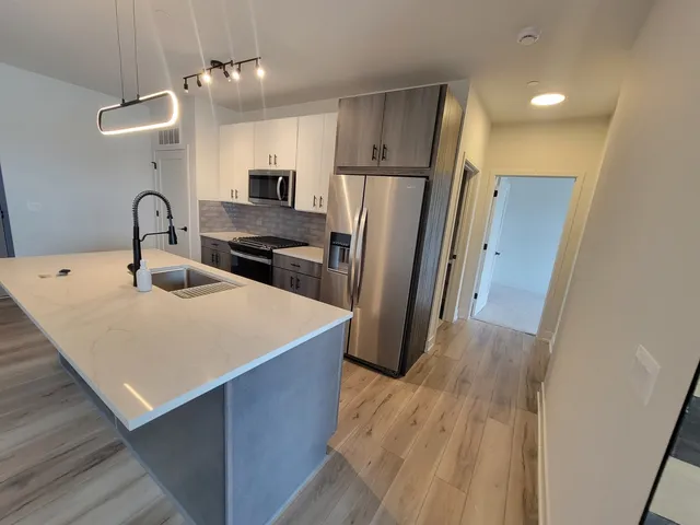 a kitchen with stainless steel appliances a refrigerator a sink a stove a microwave and island