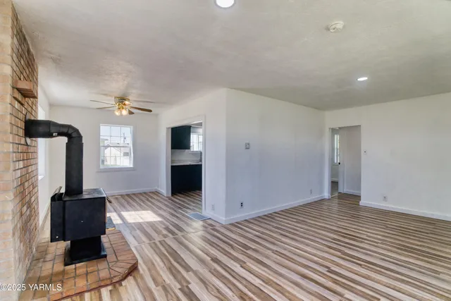 an empty room with wooden floor fireplace and windows