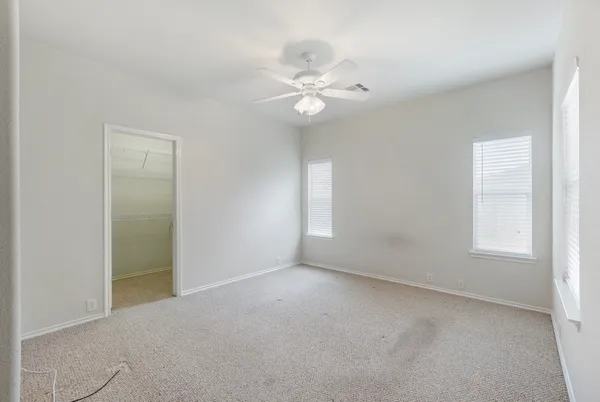 an empty room with windows and fan