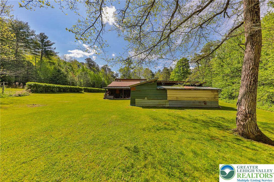 331 Cranberry Creek Road Cresco, PA 18326 - Photo 67 of 95 A tranquil expanse of green lawn unfolds, bordered by a dense line of mature trees and distant hills.