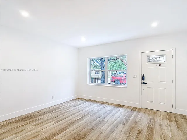 an empty room with wooden floor and window