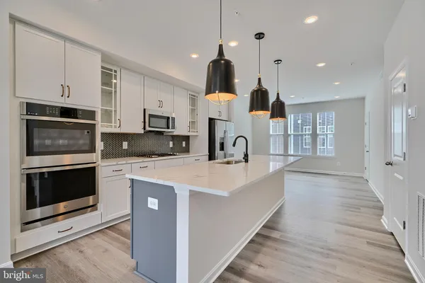 a large kitchen with stainless steel appliances kitchen island granite countertop a stove a sink and a microwave