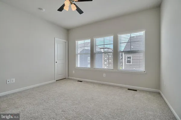 an empty room with chandelier fan and windows