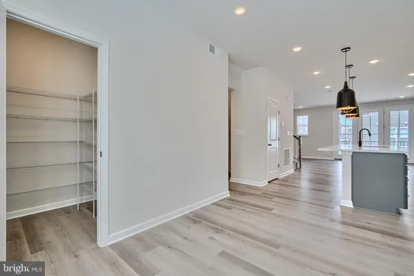 a view of a kitchen and an empty room with wooden floor