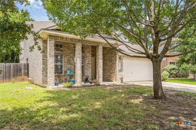 a view of a house with backyard and a tree
