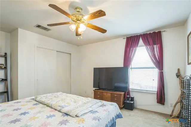 a view of a white house in front of a yard with wooden fence