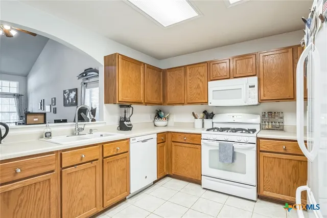 a kitchen with a stove a sink and white cabinets