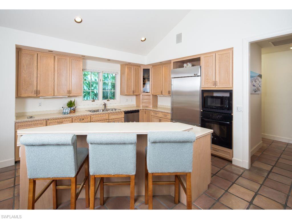 3275 Gin Lane Naples, FL 34102 - Photo 5 of 13 a kitchen with stainless steel appliances a table and chairs in it