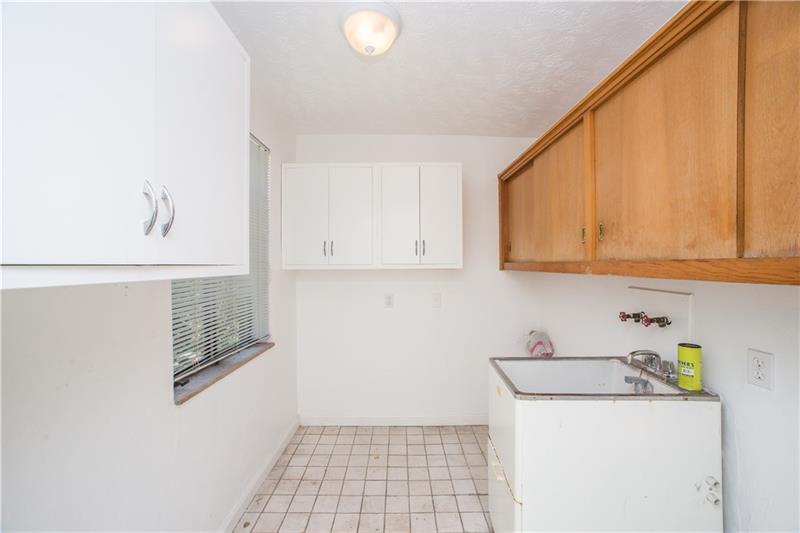 359 Beadling Road Pittsburgh, PA 15228 - Photo 13 of 25 A spacious, first-floor laundry room is conveniently located just steps away from the kitchen area. Overhead cabinetry, a large sink basin, tile flooring and window complete the space.