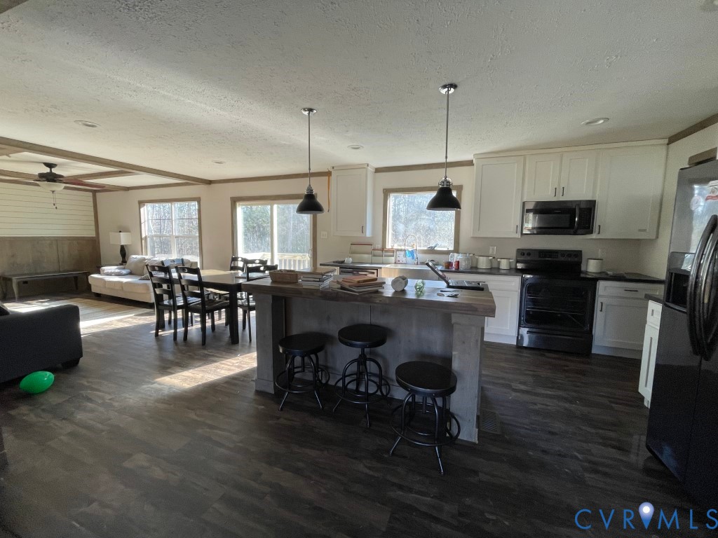 97 Buster Lane West Point, VA 23181 - Photo 10 of 32 a kitchen with kitchen island granite countertop wooden floors cabinets a dining table and appliances