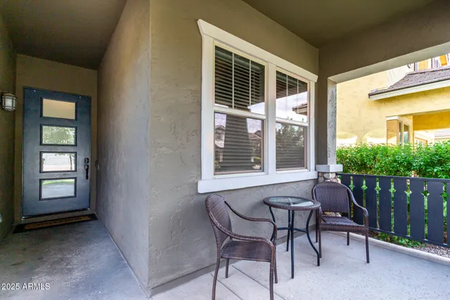 a balcony with table and chairs and potted plants
