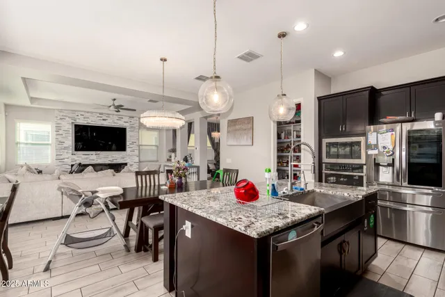 a kitchen with stainless steel appliances kitchen island granite countertop a stove a refrigerator a kitchen island a dining table and chairs