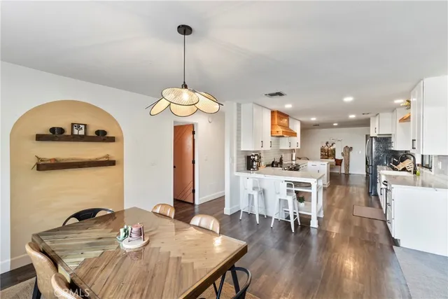 a view of a dining room and livingroom with furniture wooden floor a chandelier