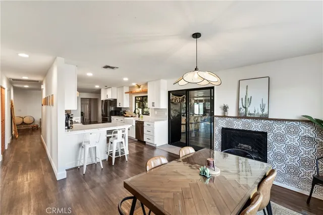 a dining room with furniture wooden floor a rug a fireplace and a chandelier