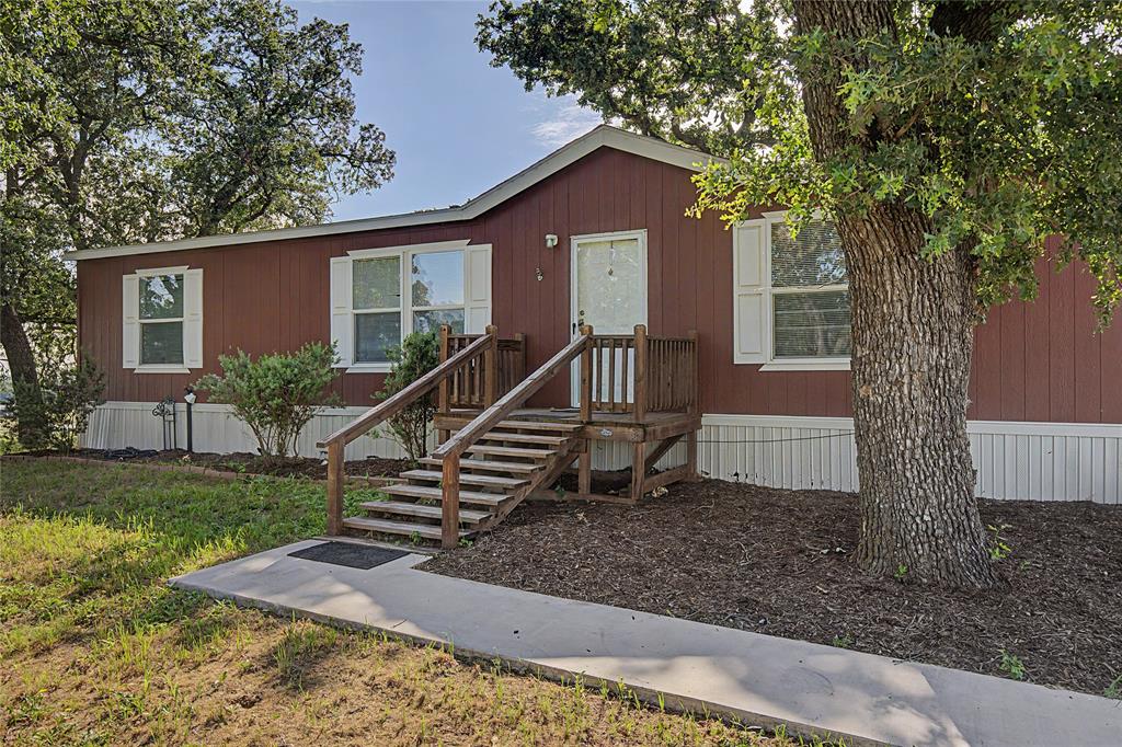 177 New Highland Road Springtown, TX 76082 - Photo 2 of 40 Single storyresidence featuring a front entry deck with wooden stairs and railing