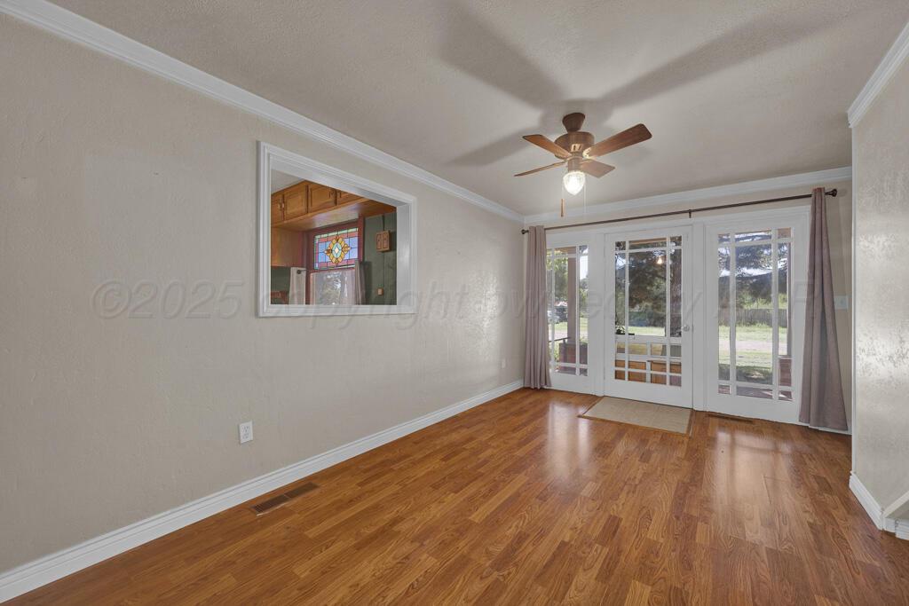 404 Chester Avenue Panhandle, TX 79068 - Photo 5 of 33 a view of an empty room with a window and wooden floor