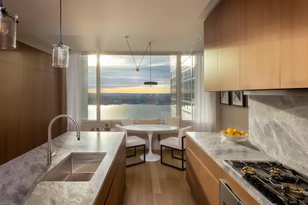 a kitchen with stainless steel appliances granite countertop a stove a refrigerator a dining table and chairs with wooden floor