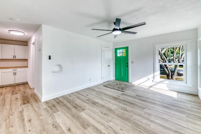 a view of an empty room with window and wooden floor