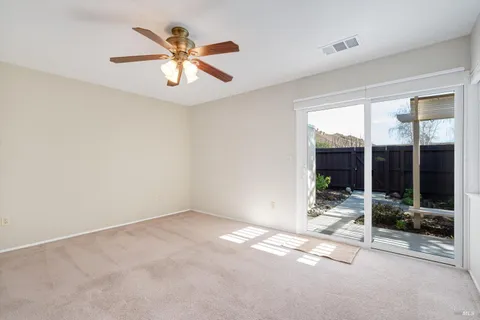 an empty room with windows and ceiling fan