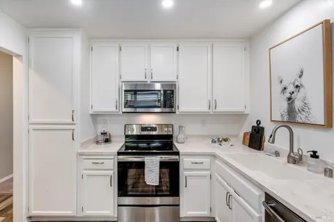a kitchen with white cabinets stainless steel appliances and sink