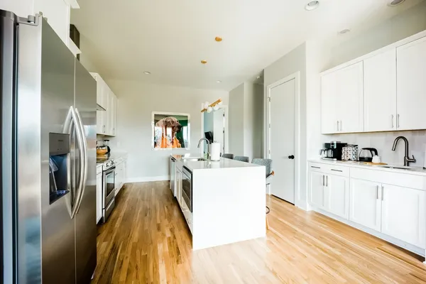 a kitchen with stainless steel appliances granite countertop a refrigerator a stove and white cabinets with wooden floor