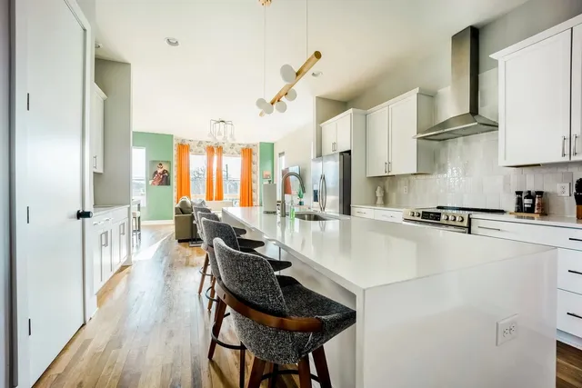 a kitchen with stainless steel appliances granite countertop a stove a refrigerator a oven a white table and chairs with wooden floor