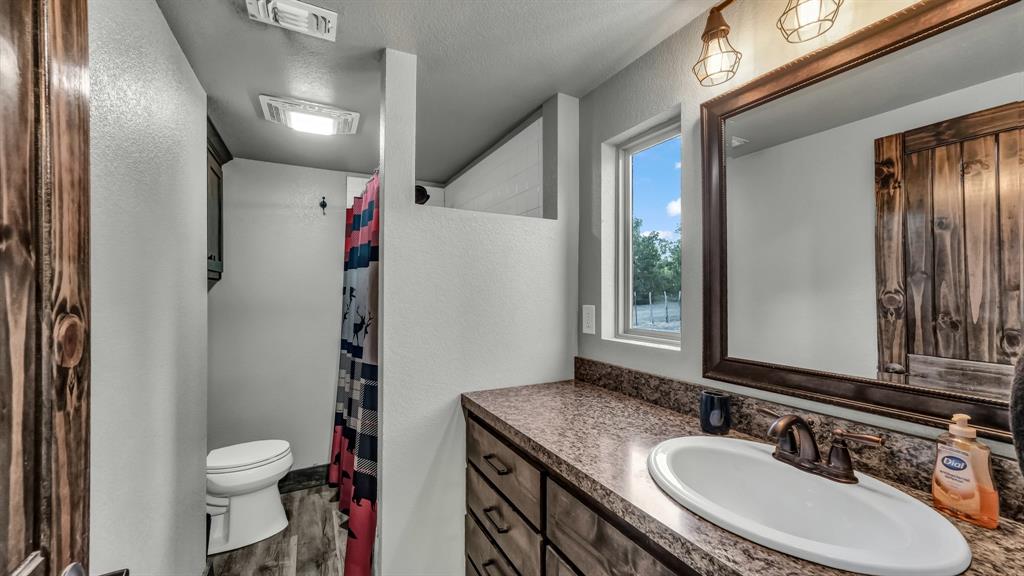 1140 Garvey Ranch Road Loving, TX 76460 - Photo 7 of 40 a bathroom with a granite countertop sink toilet and shower
